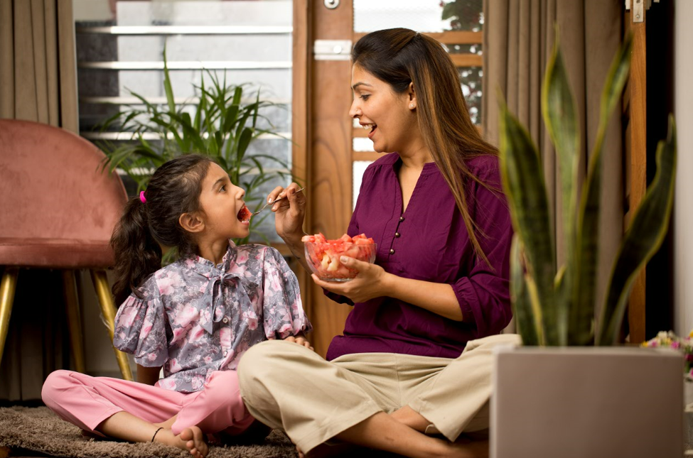 Mom feeding young girl watermelon