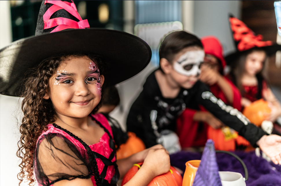 Young girl dressed as witch for trick-or-treating with friends.
