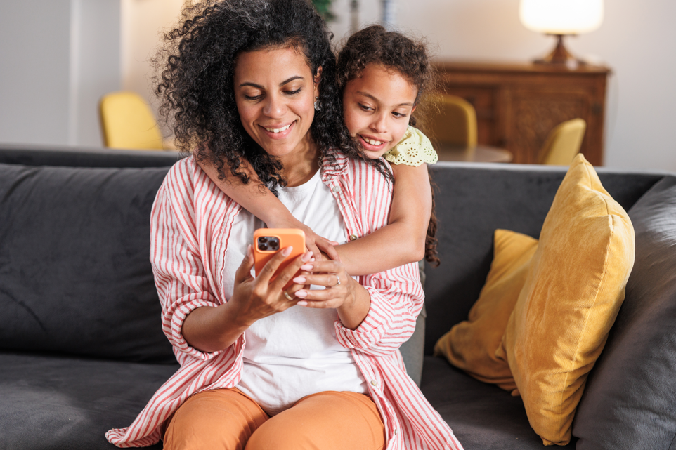 Mom on cellphone while young daugher looks on.