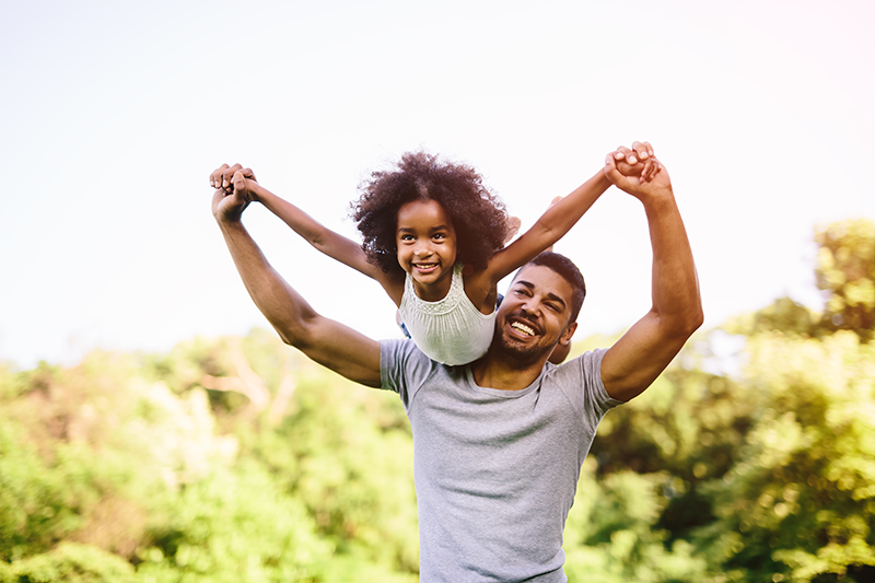 Dad lifting young girl over his shoulders.