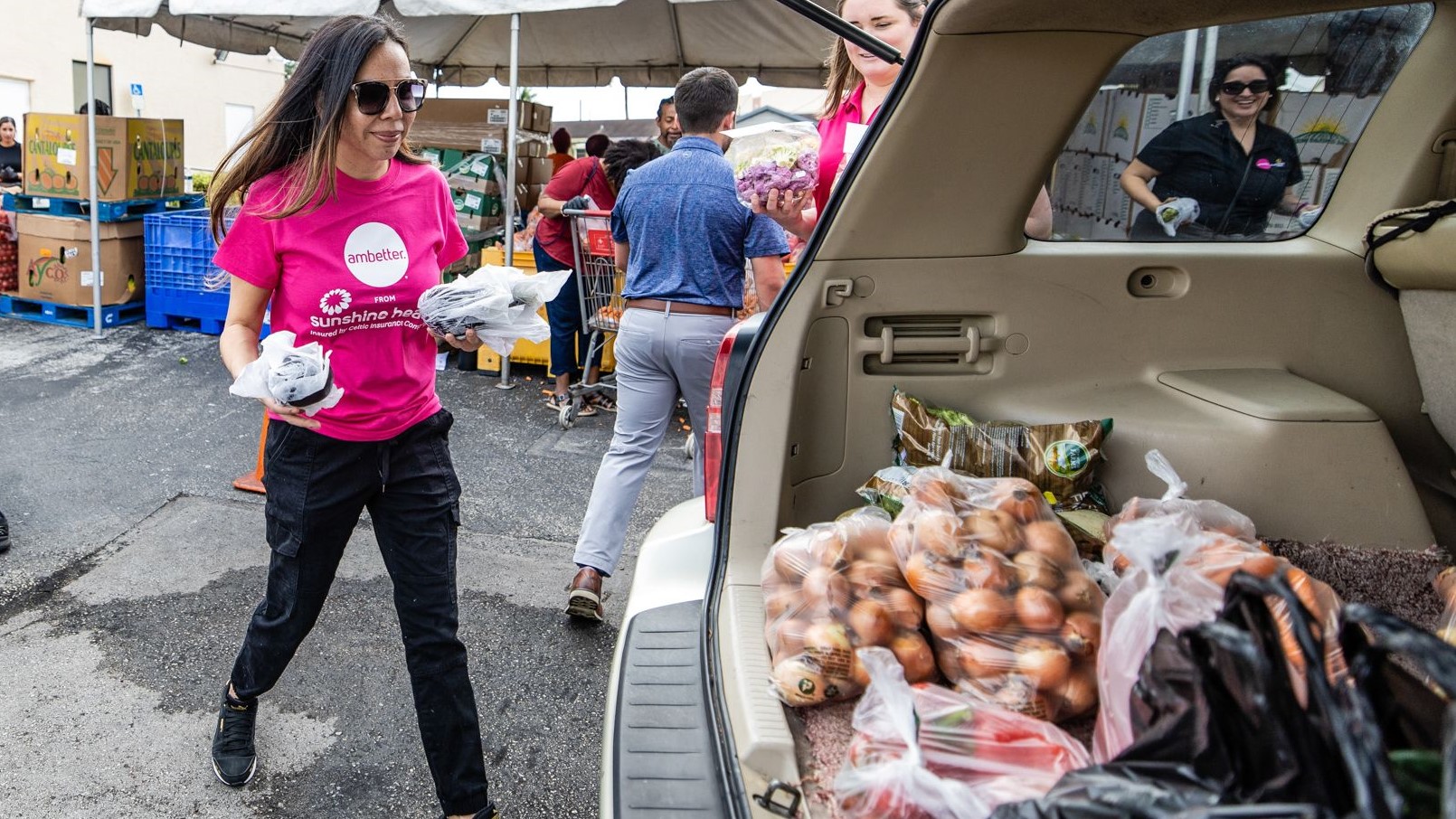 Miembros del equipo de Ambetter cargan alimentos en vehículos durante el evento.