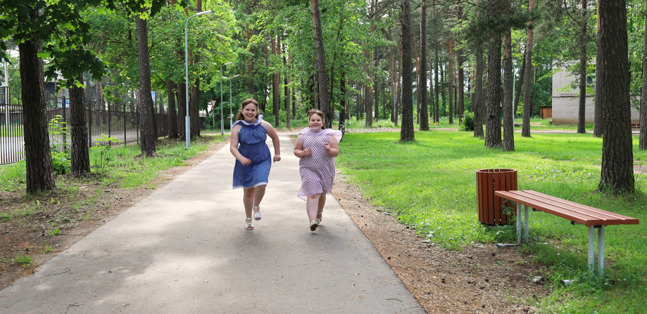 Two young girls walking on a path through a park